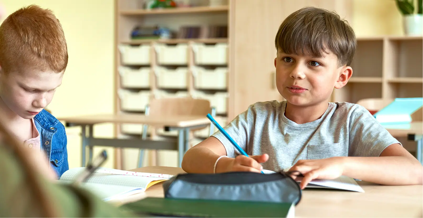 Niño escribiendo con lápiz en un cuaderno en el aula